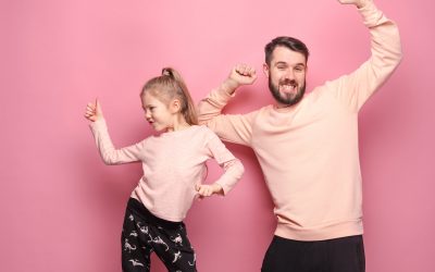 Young father with his baby daughter dancing at studio pink background
