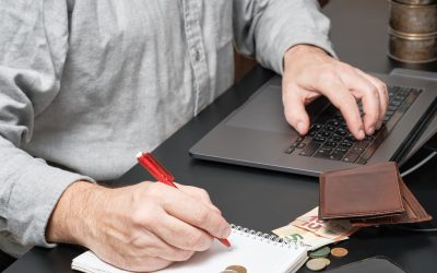 businessman-or-accountant-holding-pen-working-at-desk-using-laptop-to-calculate-financial-report